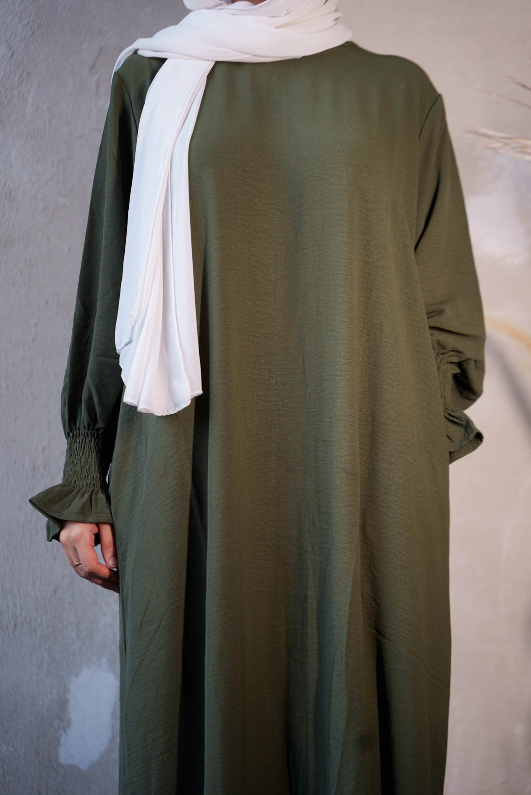 a woman in a green dress with a white scarf around her neck