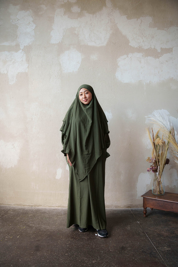 a woman in a green hijab standing in front of a wall