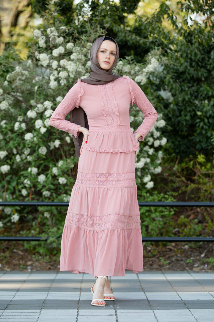 a woman wearing a hijab standing in front of a bush