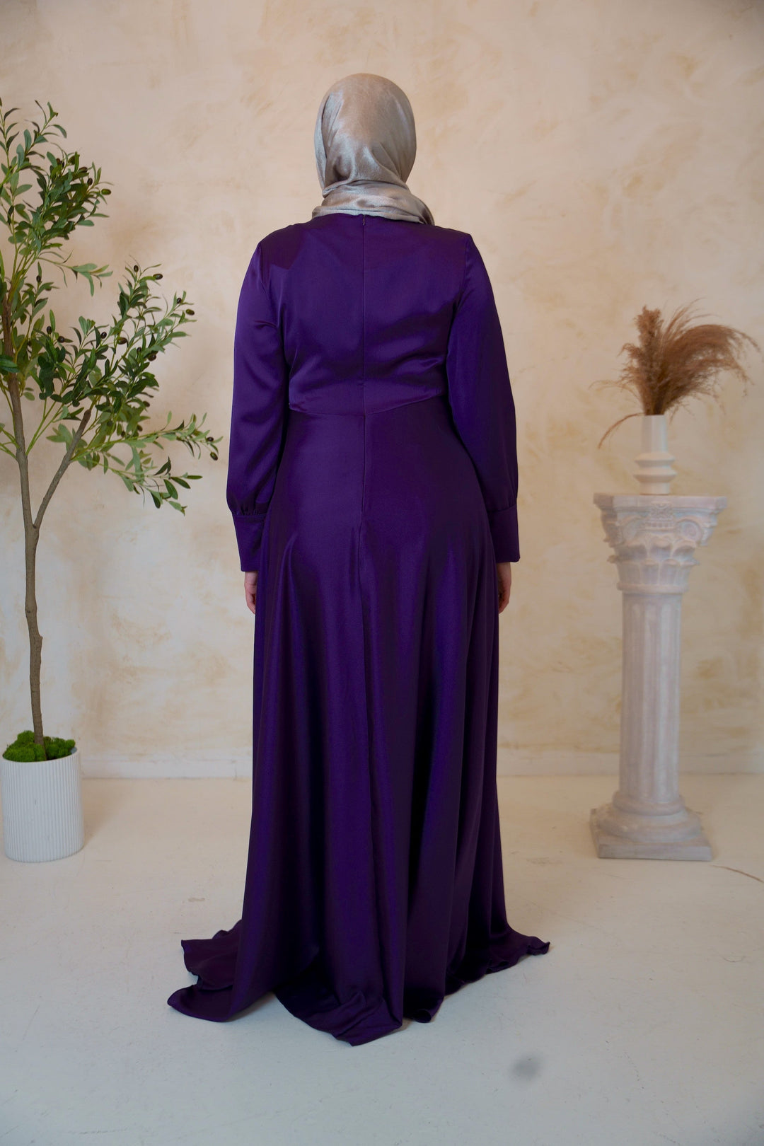 a woman in a purple dress standing next to a tree