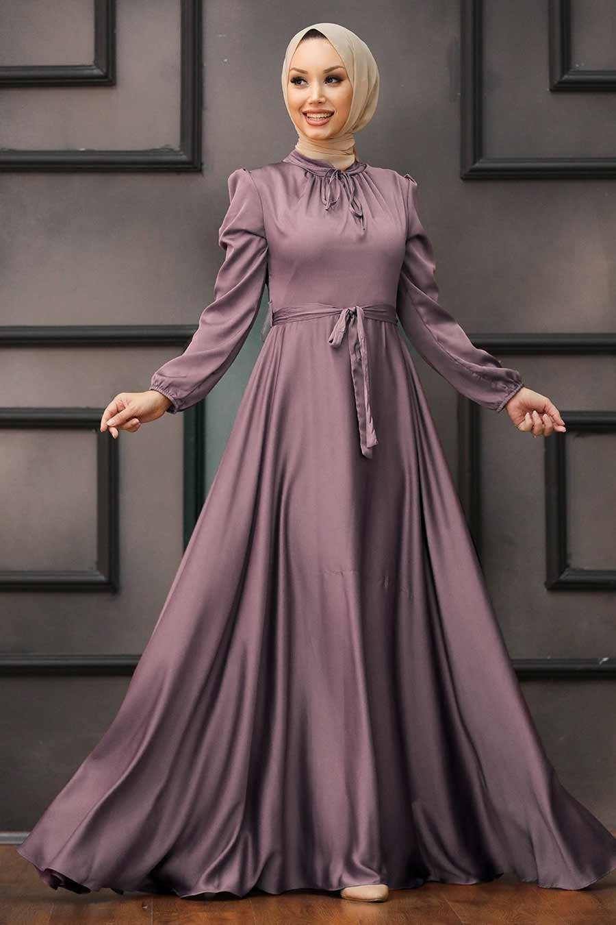 a woman in a long purple dress standing in front of a door