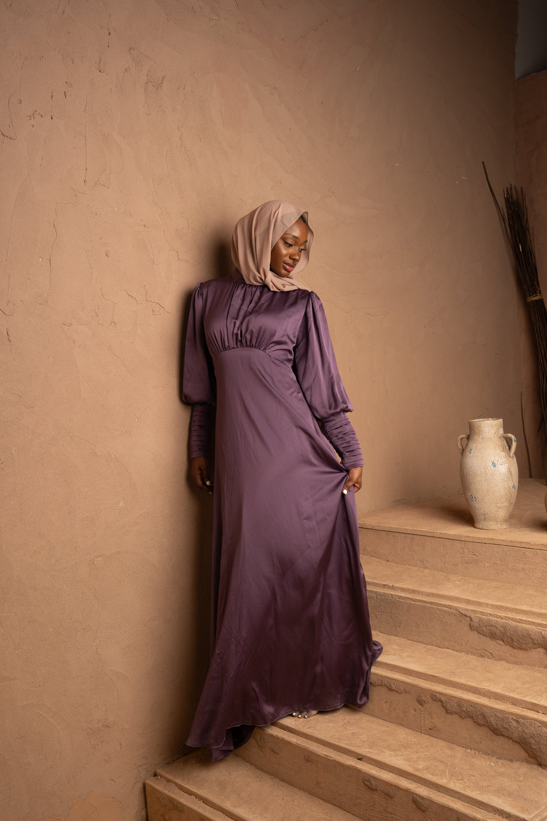 a woman in a purple dress standing on some steps