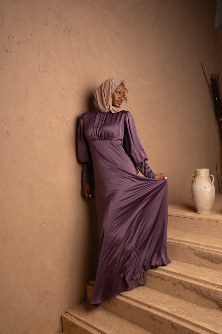 a woman in a purple dress sitting on a set of stairs