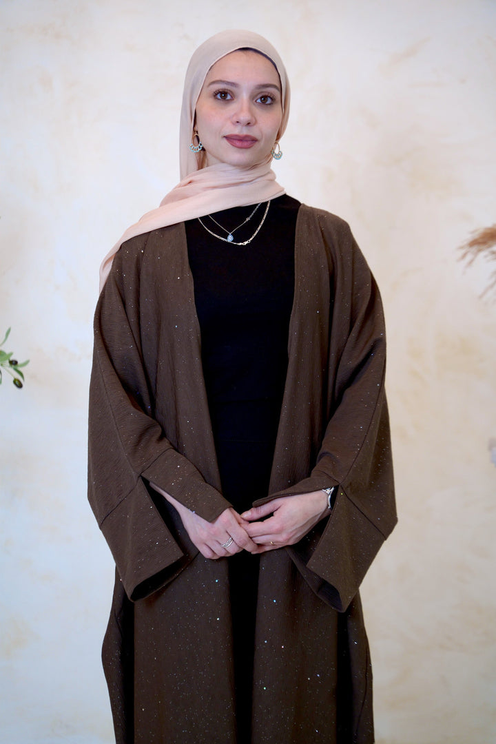 a woman wearing a brown shawl and a black top