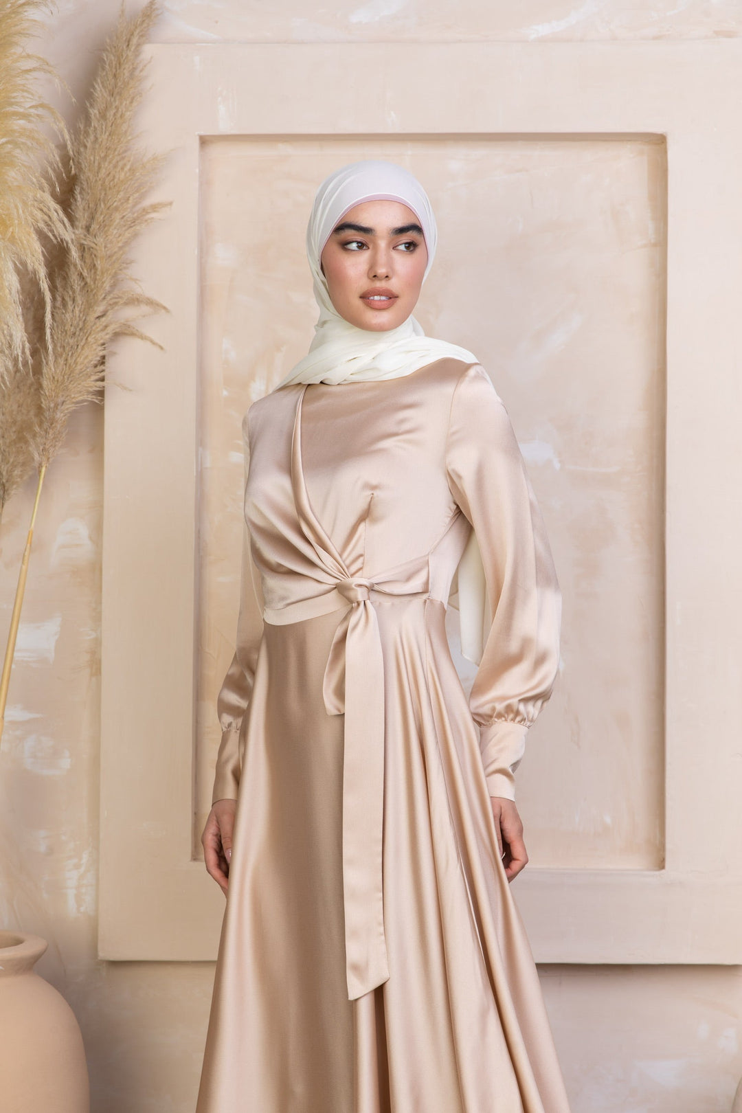 a woman wearing a beige dress with a white head scarf