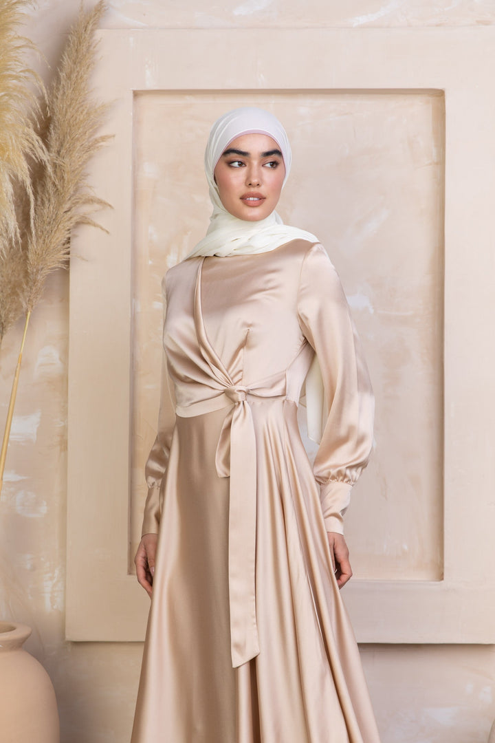 a woman wearing a beige dress with a white head scarf