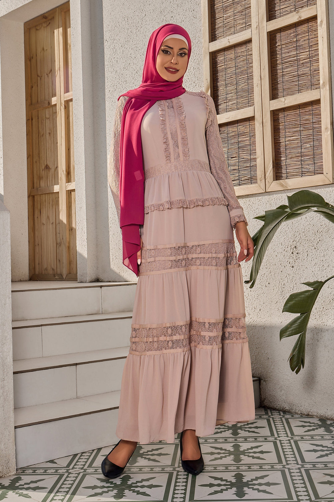 a woman wearing a pink hijab standing in front of a building