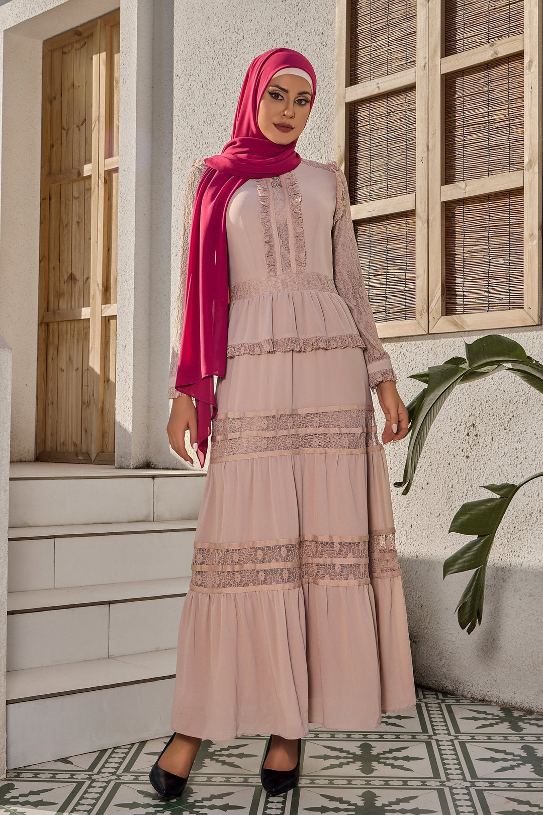 a woman wearing a pink hijab standing in front of a building