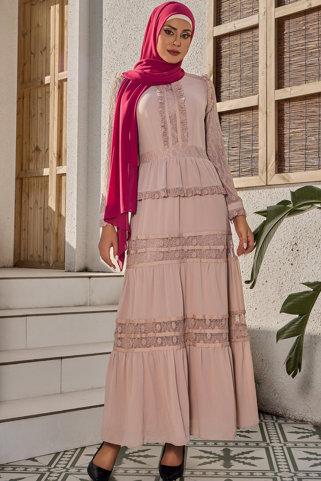 a woman wearing a pink hijab standing in front of a building