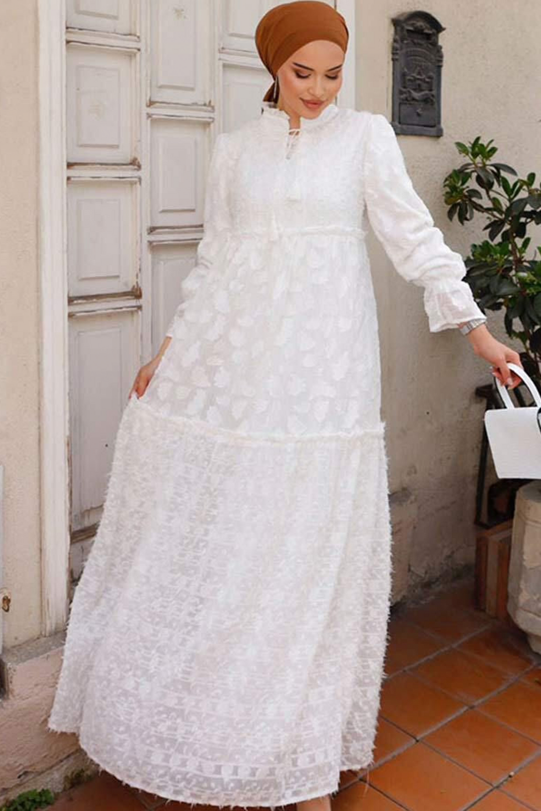 a woman wearing a white dress and carrying a white bag