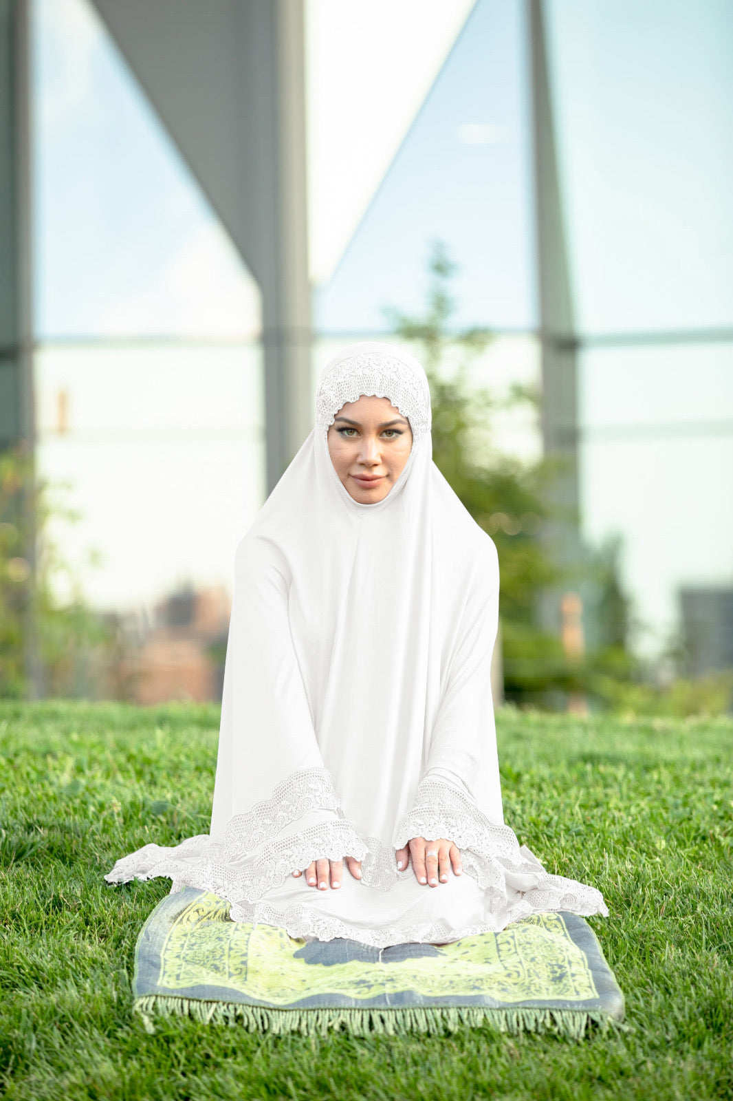 a woman in a white outfit sitting on a blanket in the grass