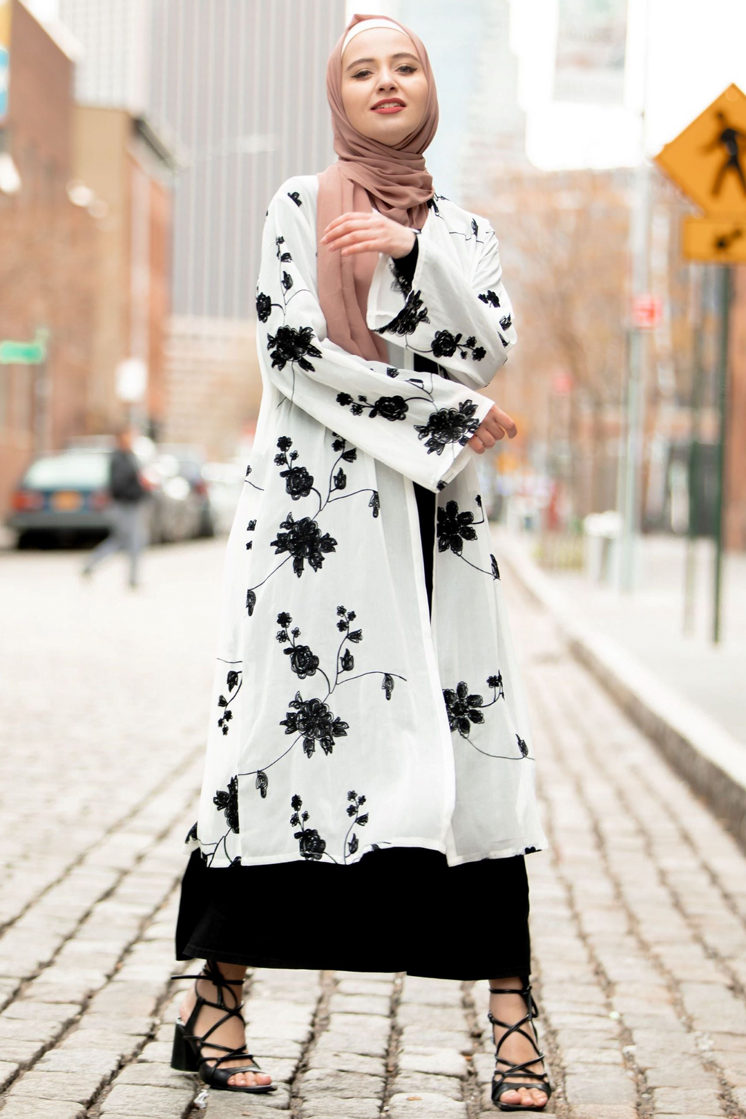 Woman in floral abaya wearing a black embroidered sheer midi cardigan