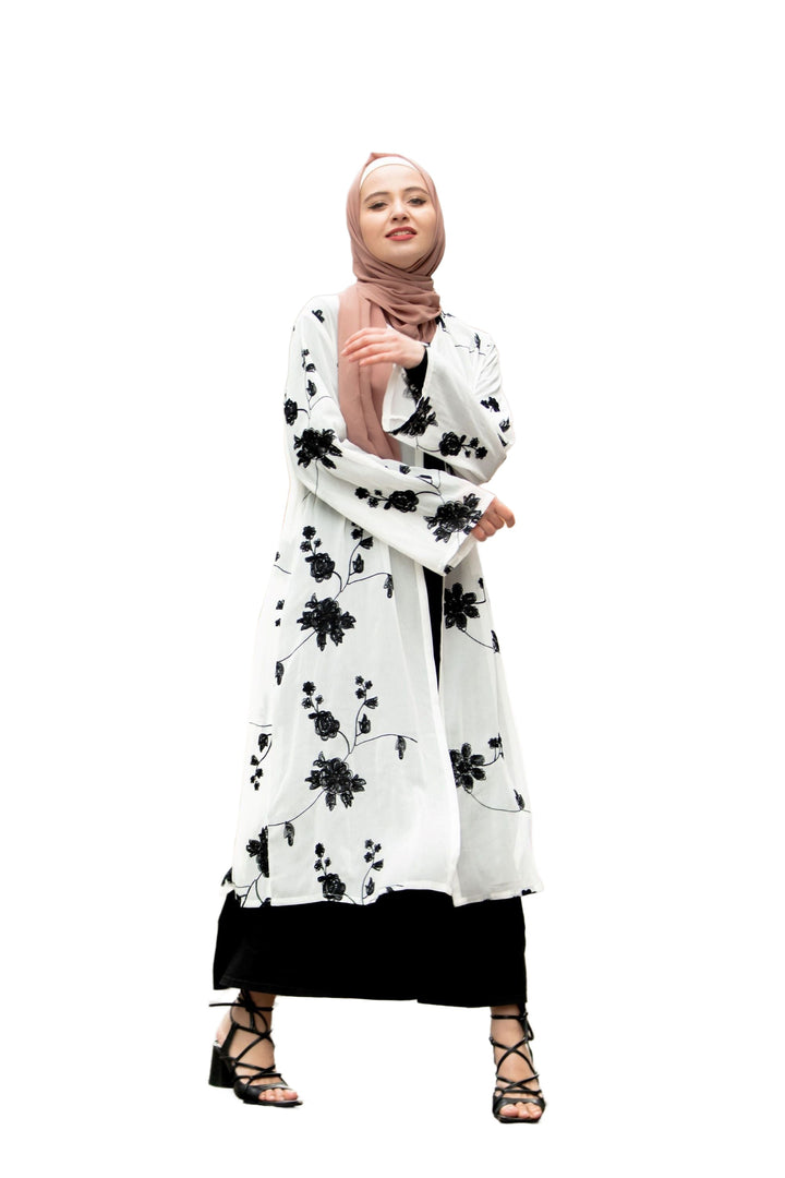 Woman wearing a floral abaya and hijab with a black embroidered sheer midi cardigan