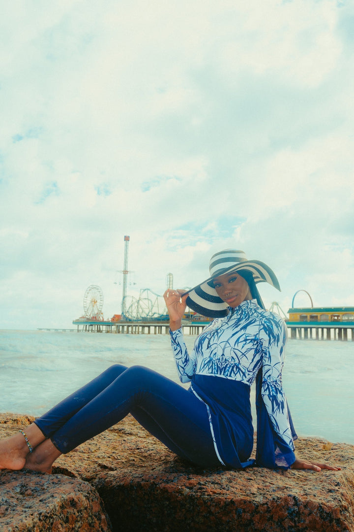 Woman wearing a White and Navy Floral 3 Piece Modest Swimsuit with a stylish hat