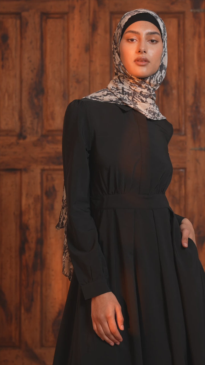 a woman wearing a black dress and a headscarf